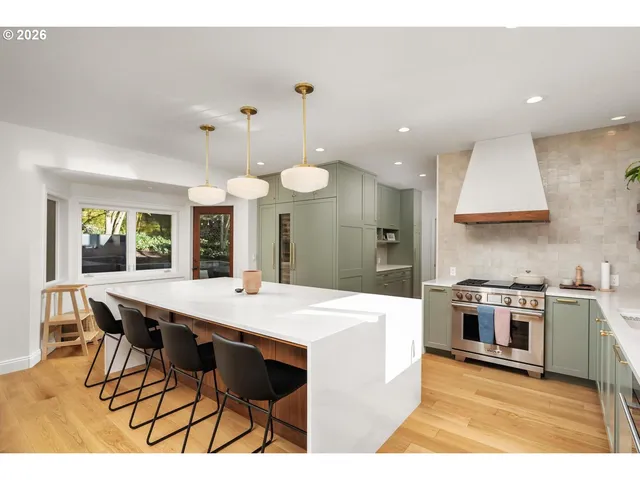 a large kitchen with stainless steel appliances a stove a dining table and chairs with wooden floor