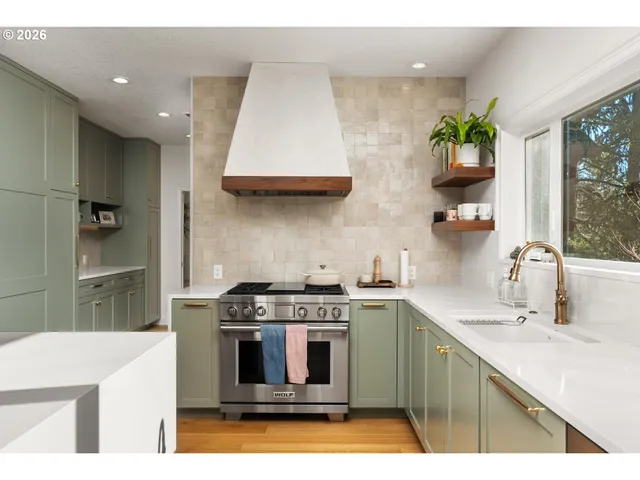 a kitchen with stainless steel appliances a sink a stove a chimney a refrigerator and cabinets