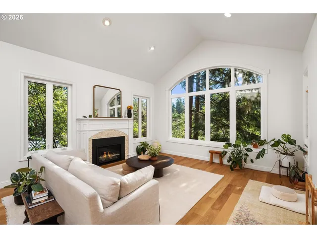 a living room with furniture and a fireplace with large windows