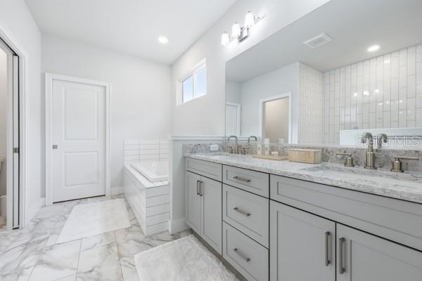 534 Southwest 145th Drive Newberry, FL 32669 - Photo 20 of 38 a spacious bathroom with a granite countertop sink a toilet a mirror and vanity
