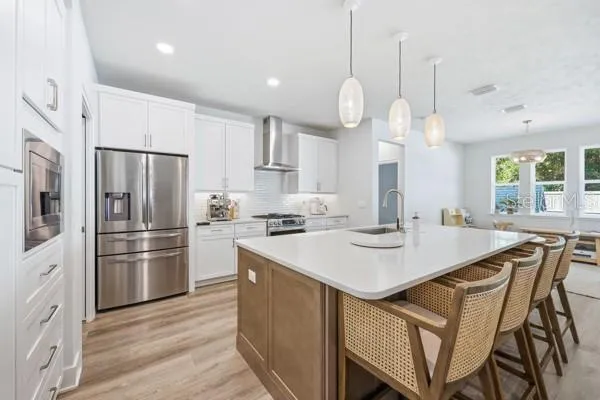 a kitchen with stainless steel appliances granite countertop a sink a stove a refrigerator and island with wooden floor