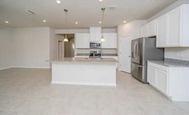 a kitchen with stainless steel appliances granite countertop a refrigerator sink and white cabinets