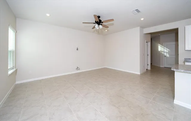 an empty room with ceiling fan and window