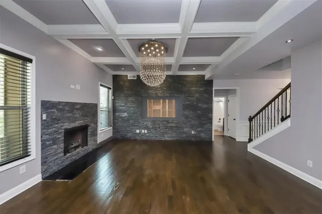 a view of an empty room wooden floor fireplace and a window