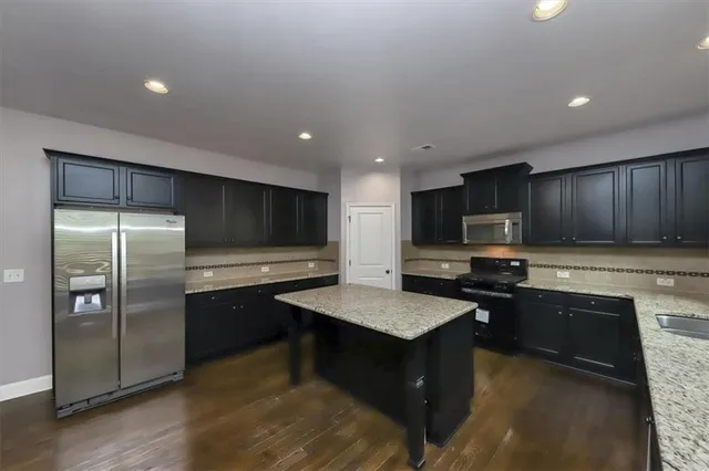 a kitchen with stainless steel appliances granite countertop a refrigerator a sink a stove a microwave and island