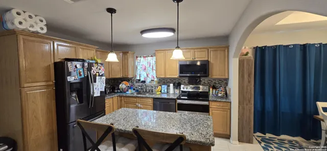 a kitchen with stainless steel appliances granite countertop a refrigerator a stove a sink dishwasher and a wooden cabinets