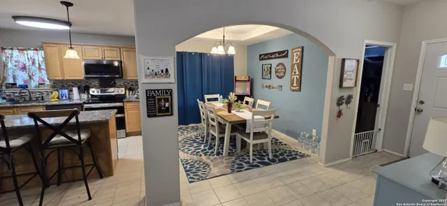 a dining room filled chandelier and kitchen view
