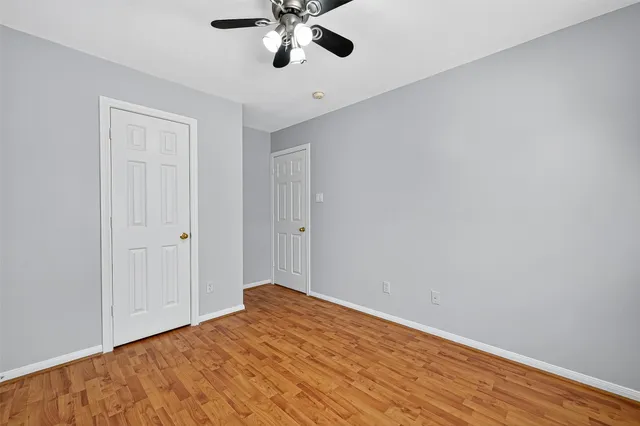 a view of empty room with wooden floor and fan