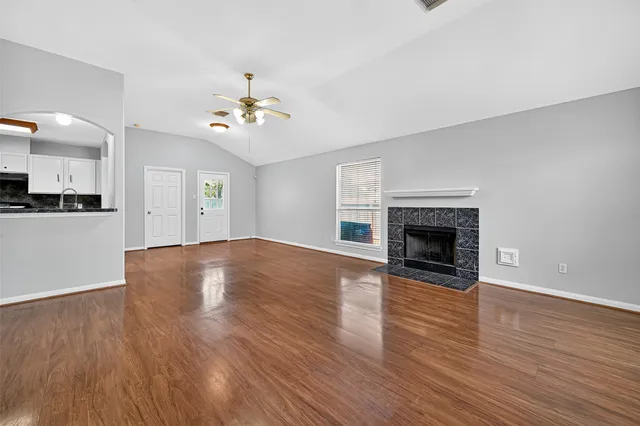 an empty room with wooden floor chandelier and windows