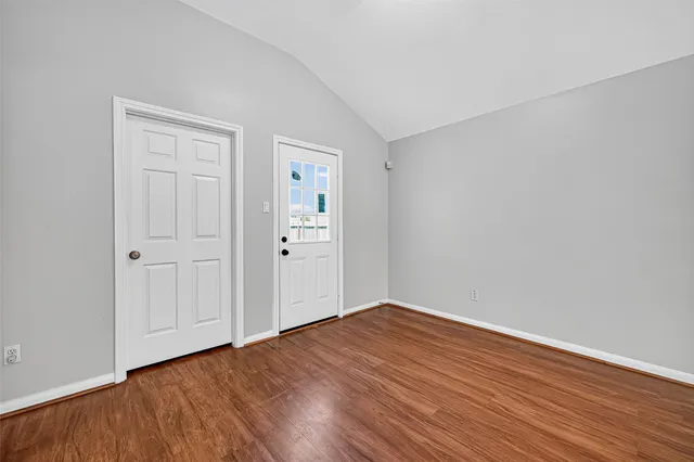 an empty room with wooden floor chandelier fan and windows
