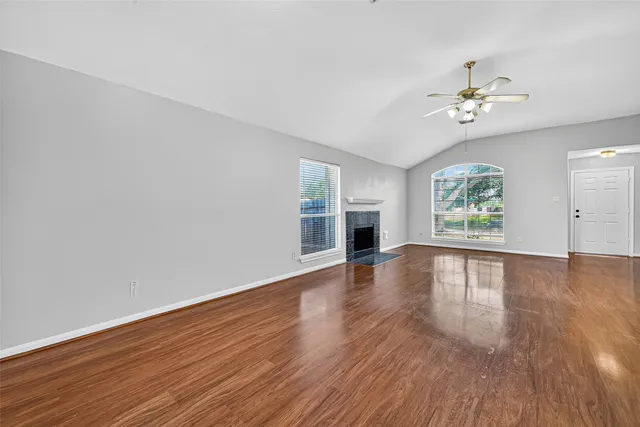 an empty room with wooden floor chandelier and windows