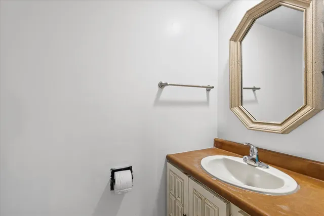 a view of a hallway with wooden floor and a bathroom