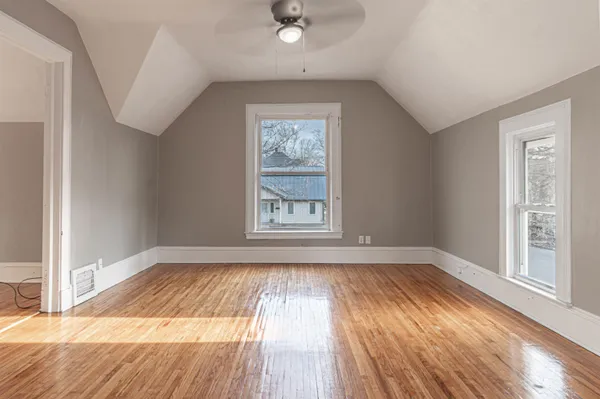 a view of an empty room with wooden floor and a window