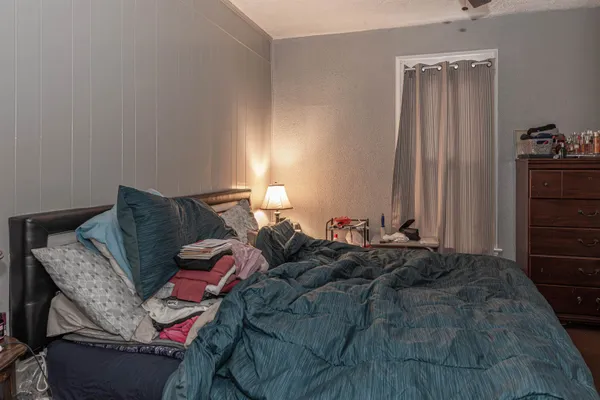 a bed sitting in a bedroom next to a window and a chair