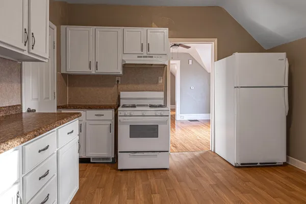 a kitchen with cabinets appliances and wooden floor