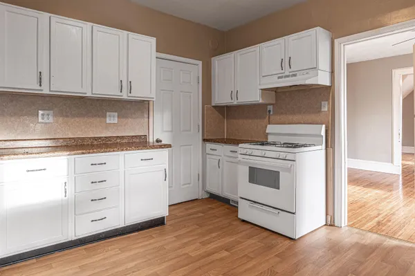 a kitchen with granite countertop white cabinets and white appliances