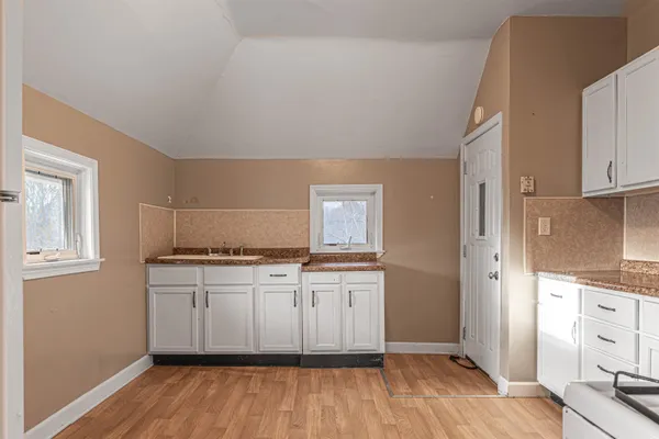 a kitchen with stainless steel appliances a stove a sink and white cabinets with wooden floor