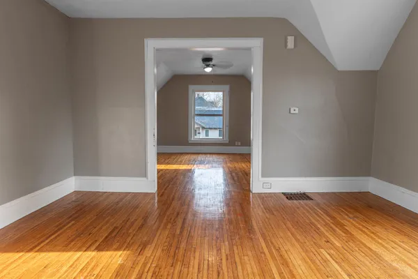 a view of empty room with wooden floor and fan