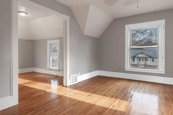 a view of an empty room with wooden floor and a window