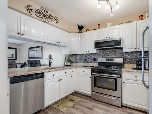 a kitchen with granite countertop white cabinets and white appliances