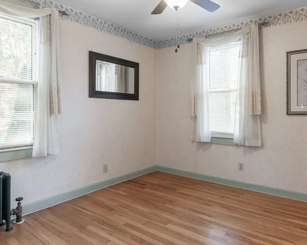 a view of empty room with wooden floor and fan