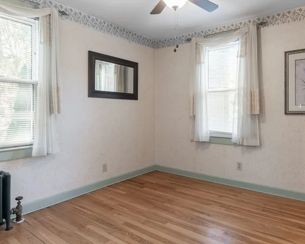 a view of empty room with wooden floor and fan