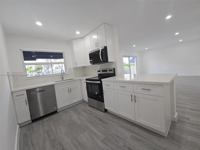 a kitchen with white cabinets stainless steel appliances a sink and a window