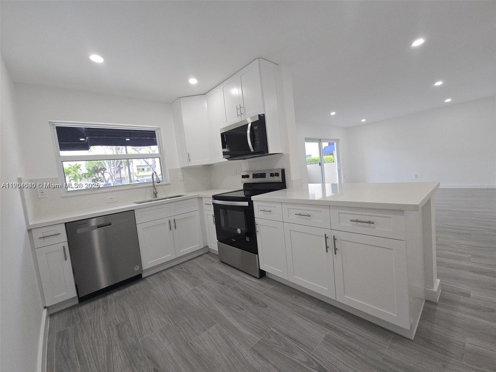 7707 Southwest 86th Street, Unit B101 Miami, FL 33143 - Photo 1 of 12 a kitchen with white cabinets stainless steel appliances a sink and a window