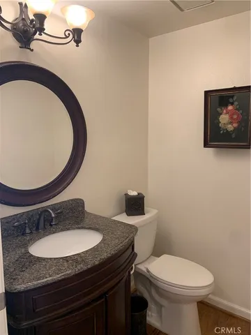 a bathroom with a granite countertop toilet sink mirror and vanity