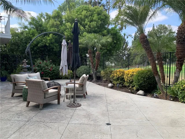 a view of a patio with a table and chairs under an umbrella with large trees