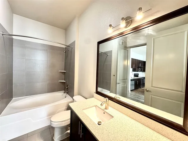 a bathroom with a bathtub shower sink mirror and toilet