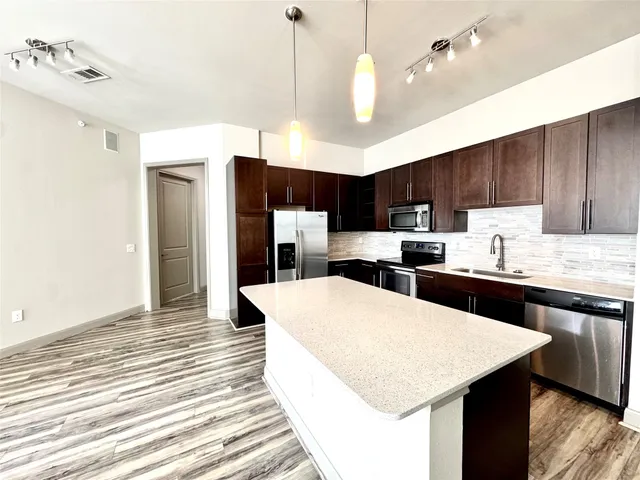 an open kitchen with kitchen island a sink stainless steel appliances and cabinets