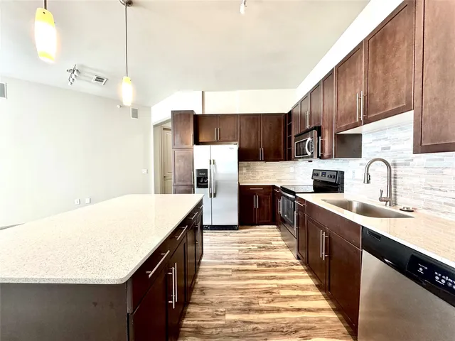 a large kitchen with stainless steel appliances kitchen island a large counter top a sink a stove and a refrigerator