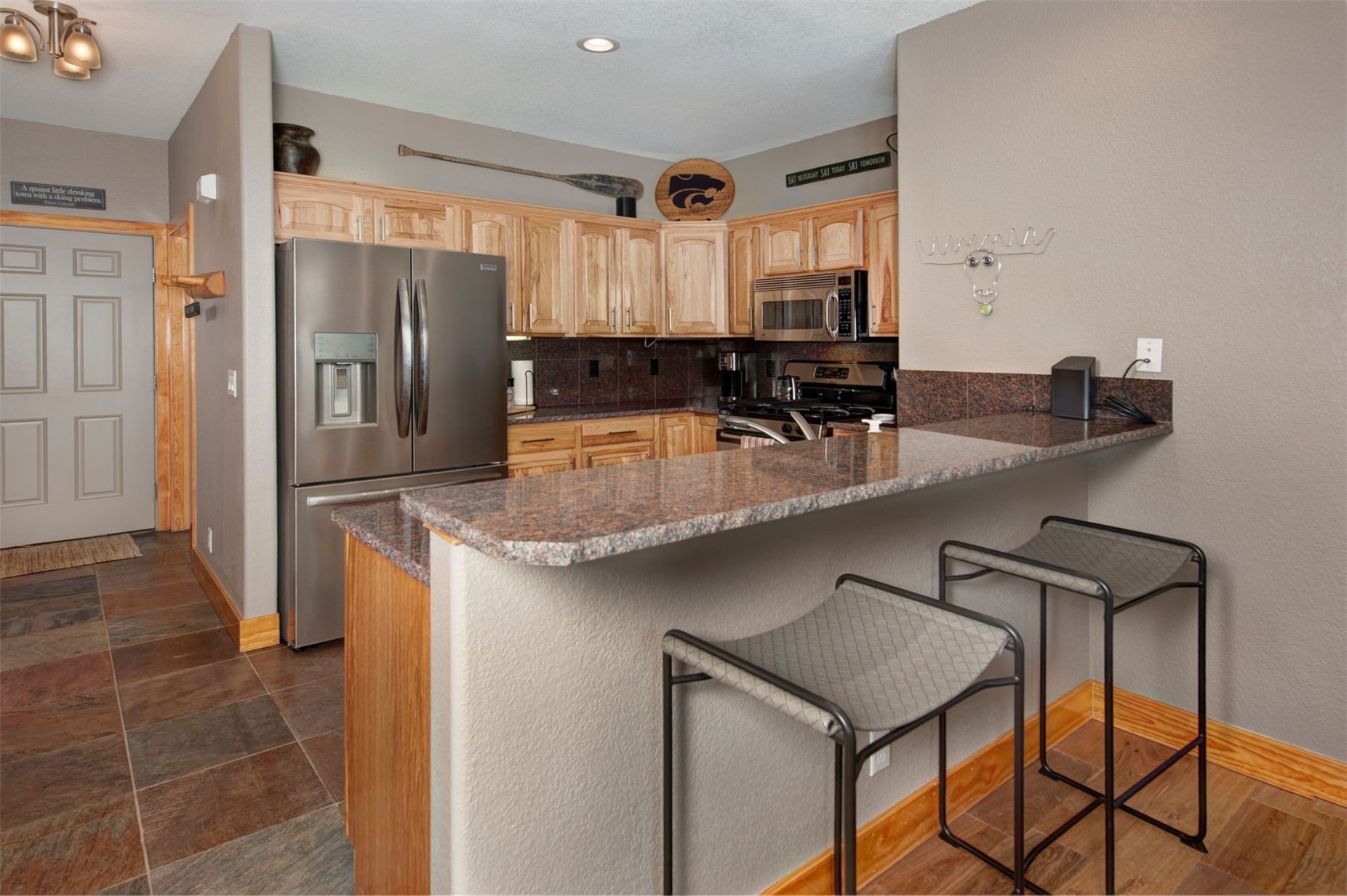 164 Buck Ridge Road, Unit 164 Dillon, CO 80435 - Photo 3 of 28 Kitchen featuring appliances with stainless steel finishes, dark stone counters, a stone fireplace, pendant lighting, and recessed lighting