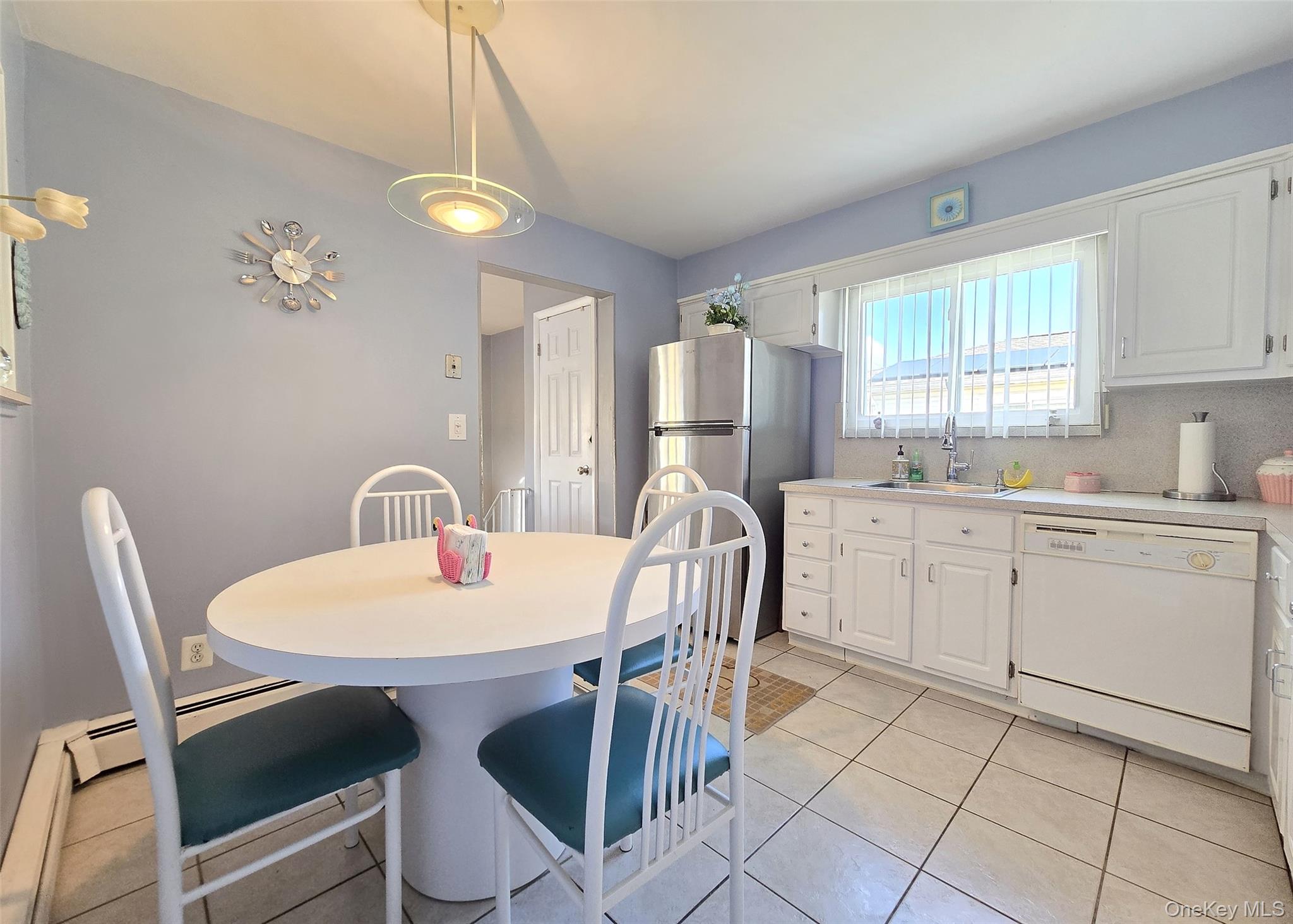 430 Heathcote Road Lindenhurst, NY 11757 - Photo 6 of 22 a kitchen with a dining table chairs and cabinets