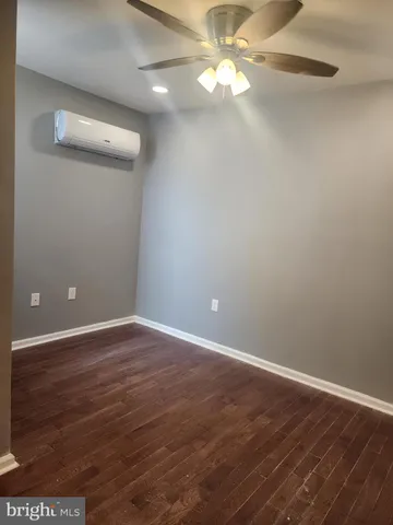 an empty room with wooden floor and fan