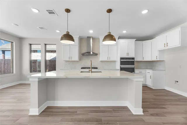 a large kitchen with granite countertop a stove a sink a center island and wooden floor