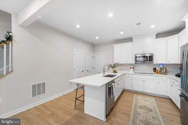 a large white kitchen with stainless steel appliances granite countertop a sink and dishwasher a stove with wooden floor