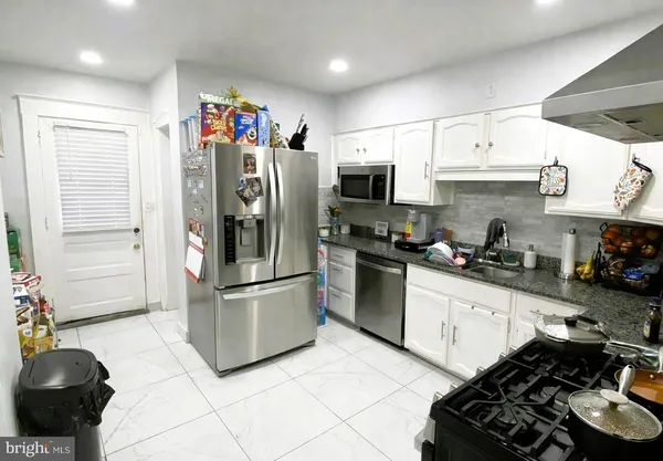 a kitchen with stainless steel appliances a refrigerator a sink a stove and cabinets