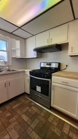 a kitchen with stainless steel appliances a stove a sink and white cabinets