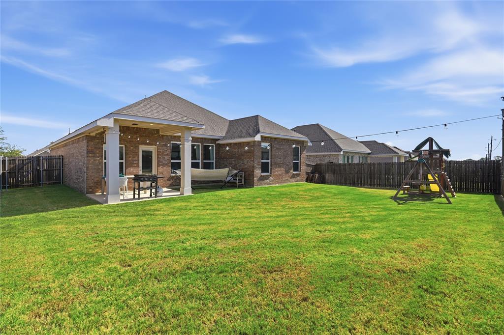 303 Ranch Road Justin, TX 76247 - Photo 12 of 14 Expansive green lawn with a covered patio featuring square columns, a brick exterior, and a wooden privacy fence