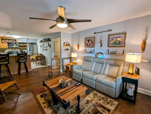 a kitchen with stainless steel appliances granite countertop a stove a refrigerator a kitchen island a dining table and chairs with wooden floor