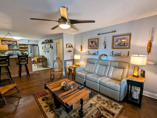 a kitchen with stainless steel appliances granite countertop a stove a refrigerator a kitchen island a dining table and chairs with wooden floor