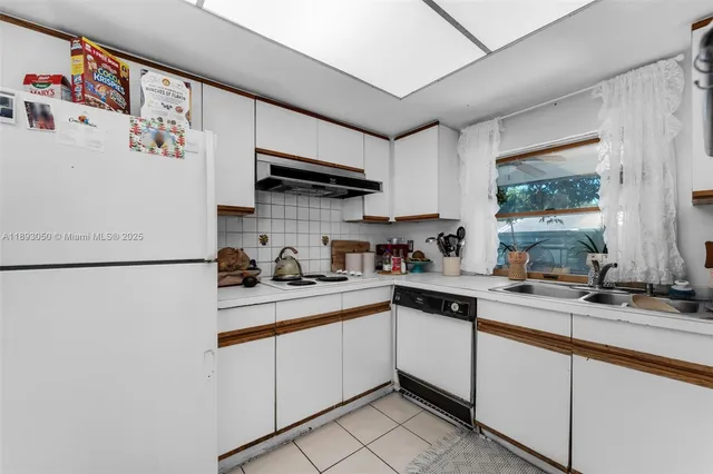 a kitchen with stainless steel appliances granite countertop a sink a stove a refrigerator and white cabinets