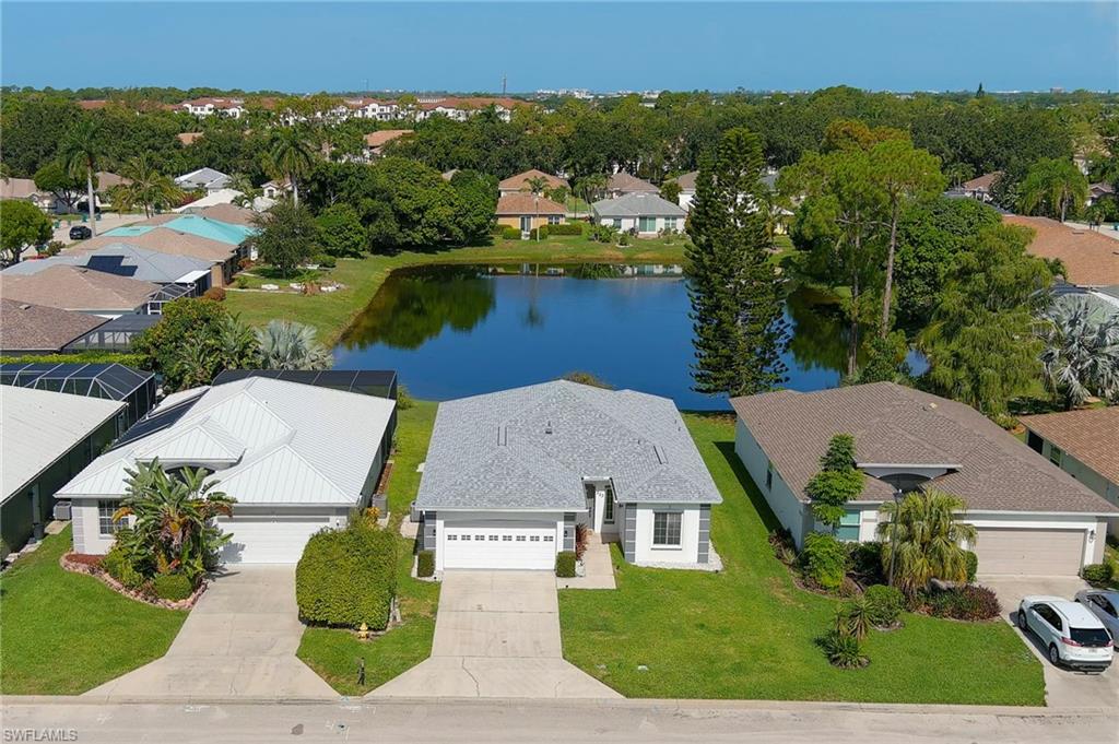 223 Stanhope Circle Naples, FL 34104 - Photo 1 of 41 Modern single-story residence featuring a gray shingled roof and an attached two-car garage