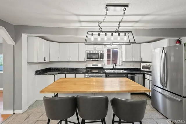 a kitchen with stainless steel appliances kitchen island granite countertop a refrigerator and microwave