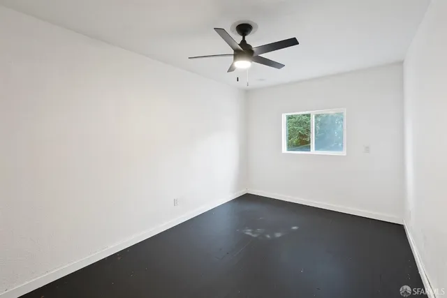 an empty room with a window and ceiling fan