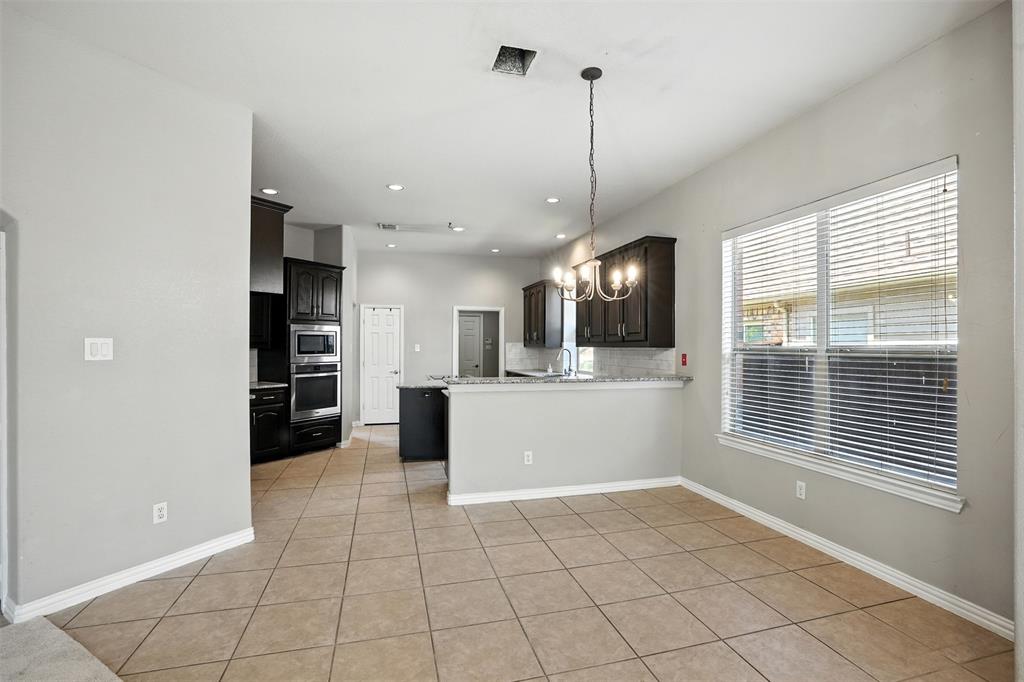 8220 Holliday Road Lantana, TX 76226 - Photo 16 of 40 Spacious dining area featuring neutral tile flooring, a multi-light chandelier, and a large window with blinds