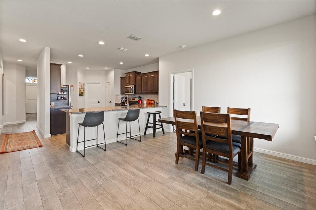 1812 Millbrae Road Cleburne, TX 76033 - Photo 13 of 30 Recessed lighting, wood-finish flooring, kitchen island with seating, built-in microwave, and dark wood-finish cabinetry