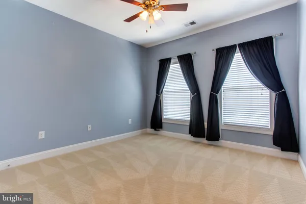an empty room with windows and ceiling fan